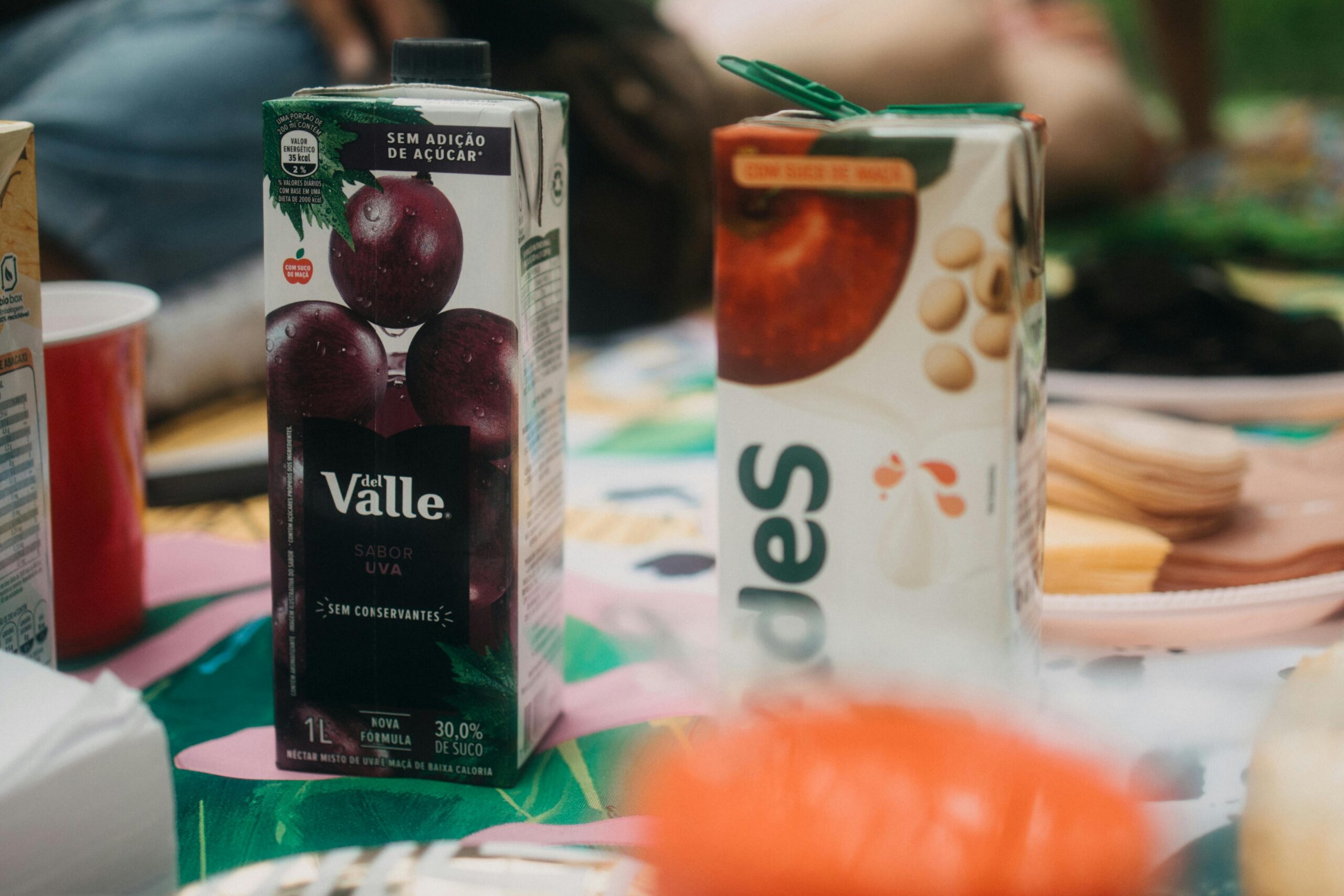 Grape and mixed beverage juice boxes on a colorful picnic table setting.